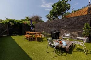 a backyard with a table and chairs and a table and a brick wall at Spacious & Welcoming 4BD House - Kennington in London