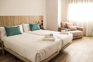 2 Betten in einem Hotelzimmer mit einem Stuhl in der Unterkunft HOTEL NARCEA in Santa Pola