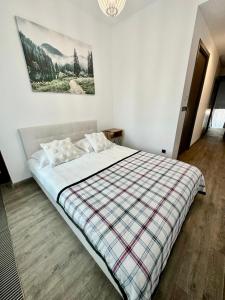a bedroom with a large bed with a plaid blanket at Apartament lux Poiana Brasov B23 in Poiana Brasov