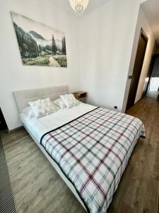 ein Schlafzimmer mit einem großen Bett mit einer karierten Decke in der Unterkunft Apartament lux Poiana Brasov B23 in Poiana Brașov