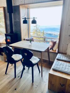 stół i krzesła w pokoju z dużym oknem w obiekcie Čudovita koča na samem, Gorenka w mieście Cerklje na Gorenjskem