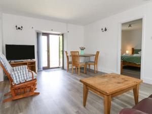 ein Wohnzimmer mit Tisch und Fernseher in der Unterkunft Clover Cottage at Pikehall in Matlock
