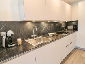 eine Küche mit weißen Schränken und einer Spüle in der Unterkunft Clover Cottage at Pikehall in Matlock + 10 Fotos