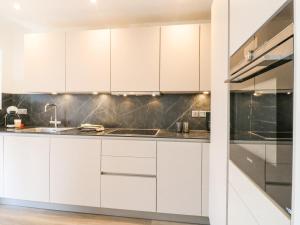 eine Küche mit weißen Schränken und einer Spüle in der Unterkunft Clover Cottage at Pikehall in Matlock