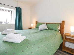 ein Schlafzimmer mit einem grünen Bett und Handtüchern darauf in der Unterkunft Clover Cottage at Pikehall in Matlock
