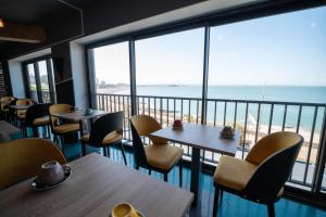 a restaurant with tables and chairs and a view of the ocean at LOGIS HOTEL - La Petite Rade in Le Havre