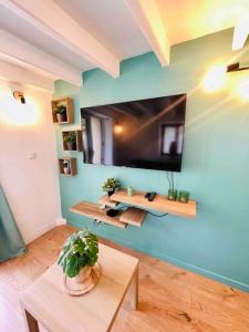 ein Wohnzimmer mit einem TV an einer blauen Wand in der Unterkunft Maisonnette au cœur de Faremoutiers in Faremoutiers