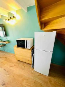eine Küche mit einem weißen Kühlschrank und einer Mikrowelle in der Unterkunft Maisonnette au cœur de Faremoutiers in Faremoutiers