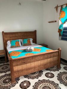 a bedroom with a wooden bed with pillows on it at Malaika House Paje in Paje