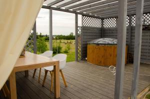 una terraza con bañera de hidromasaje, mesa y sillas en Domki na Wzgórzu - Rospuda - Domek z sauną en Filipów