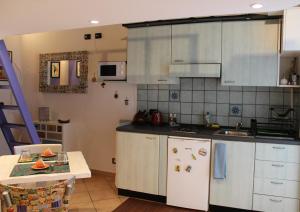 トリノにあるAppartamentino Bijouの白いキャビネット、シンク、テーブル付きのキッチンが備わります。