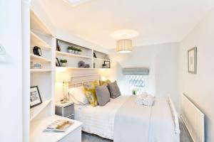 a white bedroom with a white bed and shelves at Applehoe Cottage in Bakewell