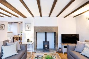 a living room with a fireplace and a tv at Applehoe Cottage in Bakewell