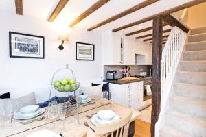 a kitchen and living room with a dining table and a staircase at Applehoe Cottage in Bakewell