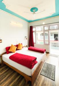 a bedroom with a large bed with red sheets at Mitra Hostel Mcleodganj in McLeod Ganj