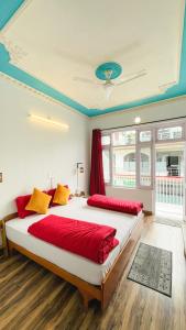 a bedroom with two beds with red and yellow pillows at Mitra Hostel Mcleodganj in McLeod Ganj