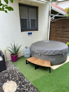 a large hot tub sitting on a lawn next to a bench at Tartane beach spa in La Trinité