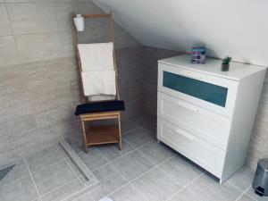 a bathroom with a white dresser and a wooden chair at Megnyugtat-LAK Vendégház in Tokaj