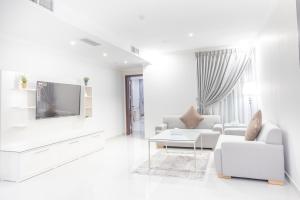 een witte woonkamer met witte meubels en een televisie bij Mooj Apartments Hotel- فندق موج للشقق الفندقية in Dammam