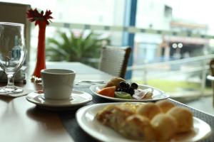 una mesa con dos platos de comida y una copa en Comfort Hotel Campos dos Goytacazes, en Campos dos Goytacazes