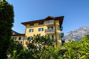 a yellow building with balconies on it with mountains in the background at Agritur Girasole in Arco
