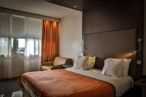 um quarto de hotel com uma cama e uma cadeira em Hôtel & Spa Vatel em Nîmes