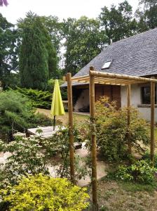 einen Garten mit gelbem Regenschirm vor einem Haus in der Unterkunft Maison dans un environnement boisé très calme in Morlaix
