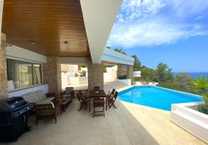a patio with a table and chairs next to a swimming pool at Ibiza 7th Heaven Villa in Sant Josep