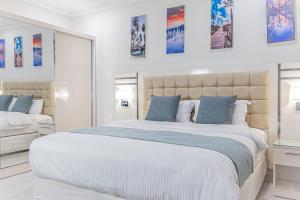 a white bedroom with a large bed with blue pillows at Mooj Apartments Hotel- فندق موج للشقق الفندقية in Dammam