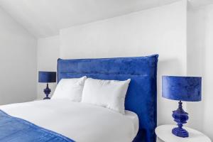 a bed with a blue headboard and two blue lamps at The Earl - Hampstead Heath in London