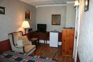a room with a bed and a tv and a chair at Hadovka Lakeside Inn in Wellington