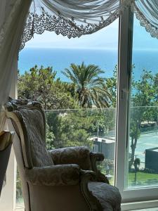 una silla frente a una ventana con el océano en Konyaaltı plajına 10 dakika kral dairesi, en Antalya