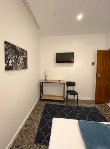 1 dormitorio con 1 cama, escritorio y TV en Taffetà b&b, en Crispiano