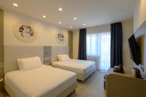 um quarto de hotel com duas camas e uma televisão de ecrã plano em Hotel & Apartments Sasso em Diano Marina