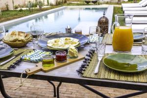 Villa Essaouira petit déjeuner compris في الصويرة: طاولة مع طعام ومشروبات بجوار حمام سباحة