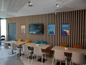 a restaurant with tables and chairs and striped walls at Aparthotel Adagio Access Le Havre Les Docks in Le Havre