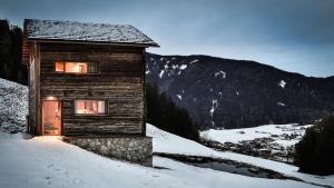 una cabina in legno nella neve con una montagna di Burgfrieder Mühle a Rasun di Sopra