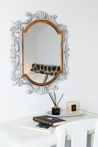 a mirror on a wall above a table with books at Villa Maina in Kamari