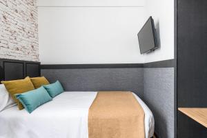 1 dormitorio con 1 cama y TV en la pared en BYPILLOW San Mamés, en Bilbao