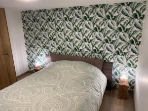 - une chambre avec un lit et du papier peint vert et blanc dans l'établissement Souplex proche de Pont-Audemer, 