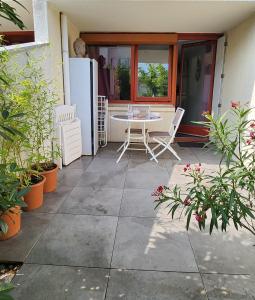 eine Terrasse mit einem Tisch, Stühlen und einem Fenster in der Unterkunft Charmant studio 2* rdc+ terrasse & parking privé in Aix-les-Bains