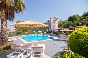 a swimming pool with chairs and an umbrella and a hotel at hotelsunnybeachgr in Perdika