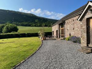 a stone house with a gravel driveway at Baddegai Holiday Cottage in Brecon