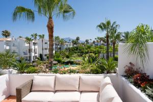 un sofá blanco sentado en un balcón con palmeras en Costalita Beach Apartment, en Estepona