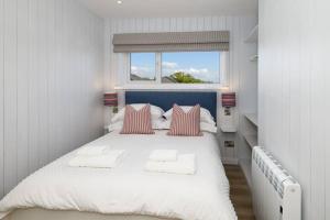 a bedroom with a white bed with pillows and a window at HIGH TIDE - Luxury 2 bed apartment with parking in Saundersfoot