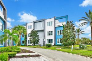 a building with palm trees in front of a road at Lovely Condo near Disney w Hotel Amenities - 7770-26-210 in Kissimmee