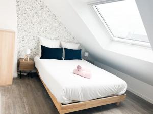 um quarto com uma cama branca com almofadas azuis e uma janela em T4 Pamplemousse Cosy proche plages et commerces em Saint-Nazaire