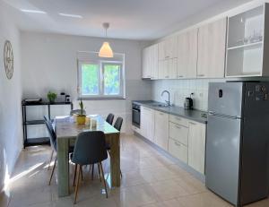 a kitchen with a dining table and a refrigerator at Kuća za odmor Bebić, Kremena in Klek