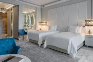 una habitación de hotel con 2 camas y una silla azul en Marchica Lagoon Resort, en Nador