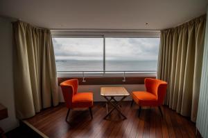 a room with two chairs and a table and a large window at LOGIS HOTEL - La Petite Rade in Le Havre